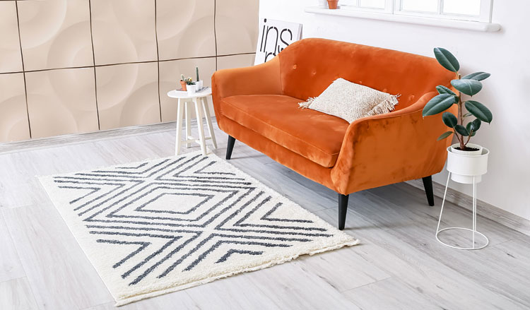 Geometryczny dywan z poliestru ułożony na podłodze przy sofie